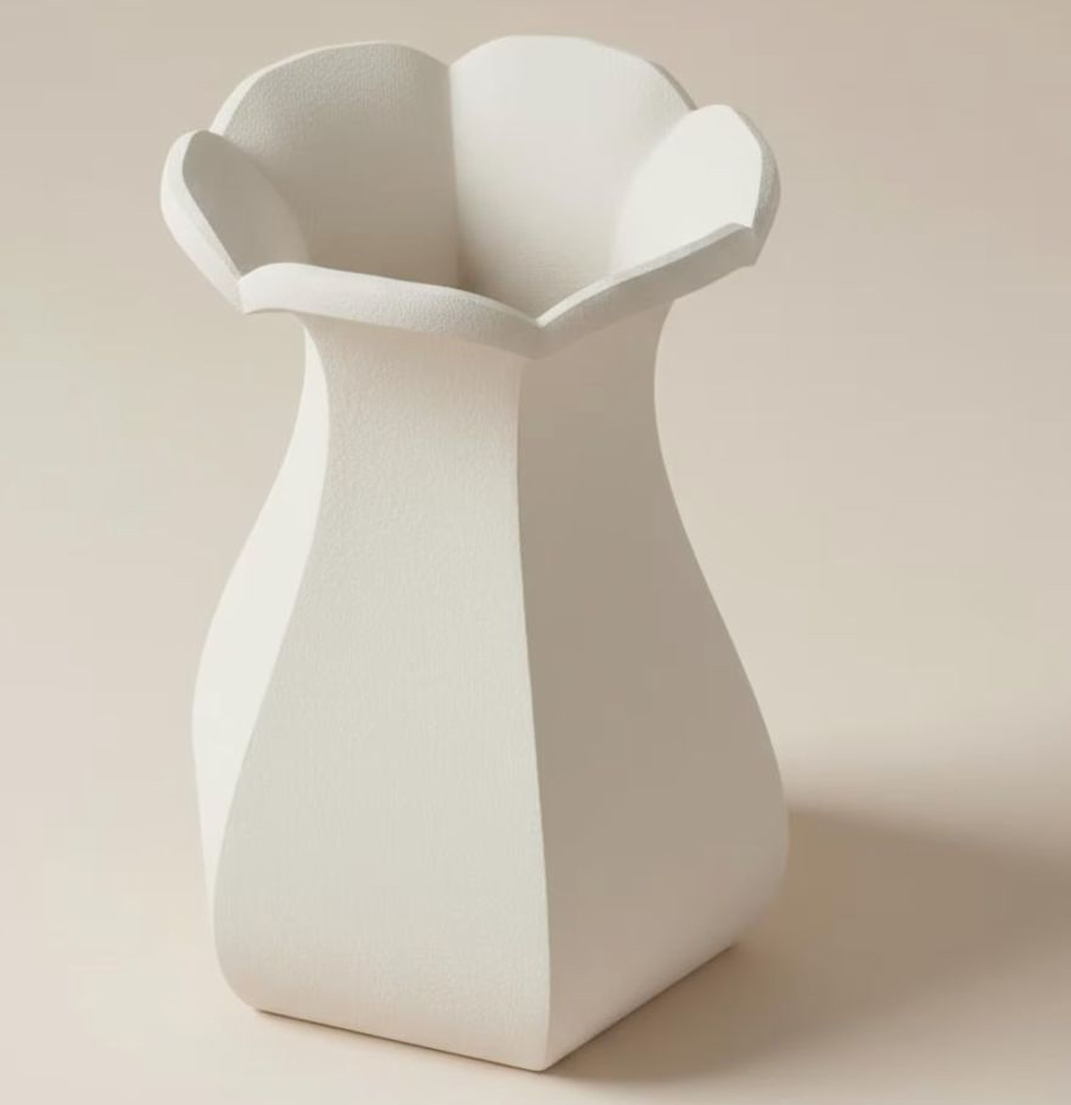 A white, geometric vase with a pointed top and flared bottom, standing alone against a light background.