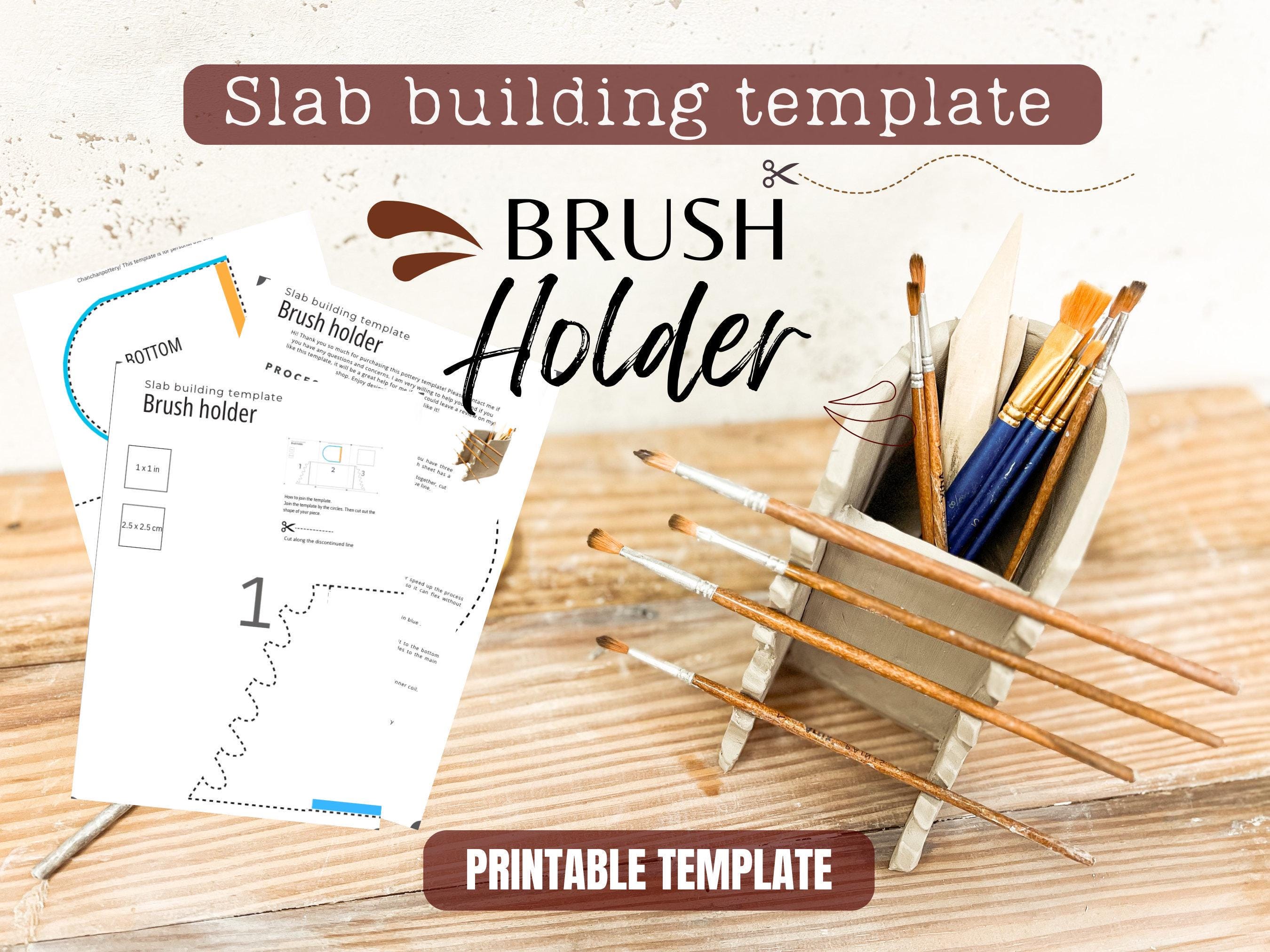 a slab building template for a brush holder, along with a set of paintbrushes and a wooden surface.