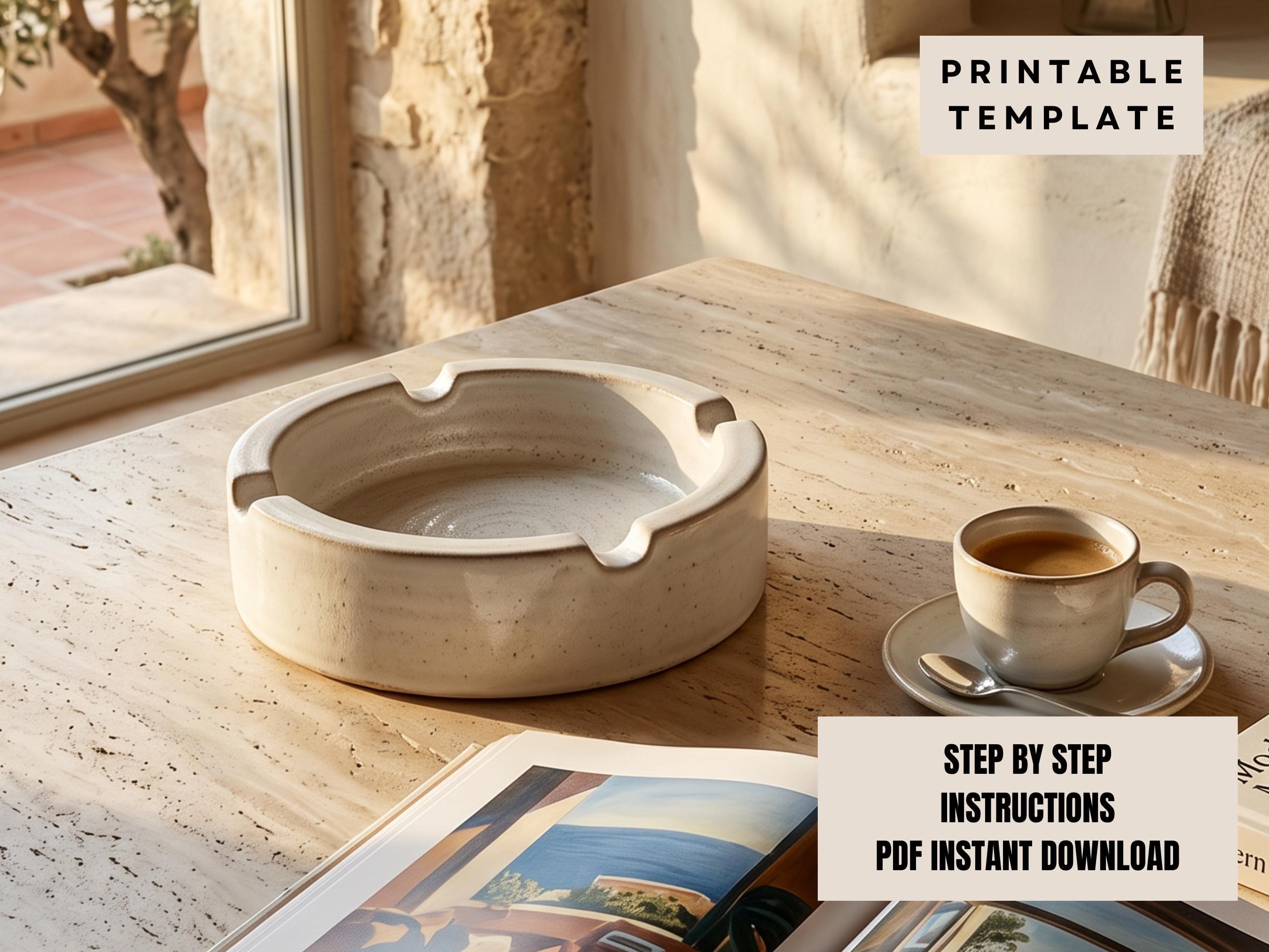 a white ceramic ashtray on a wooden table, with a cup of coffee and a magazine nearby.